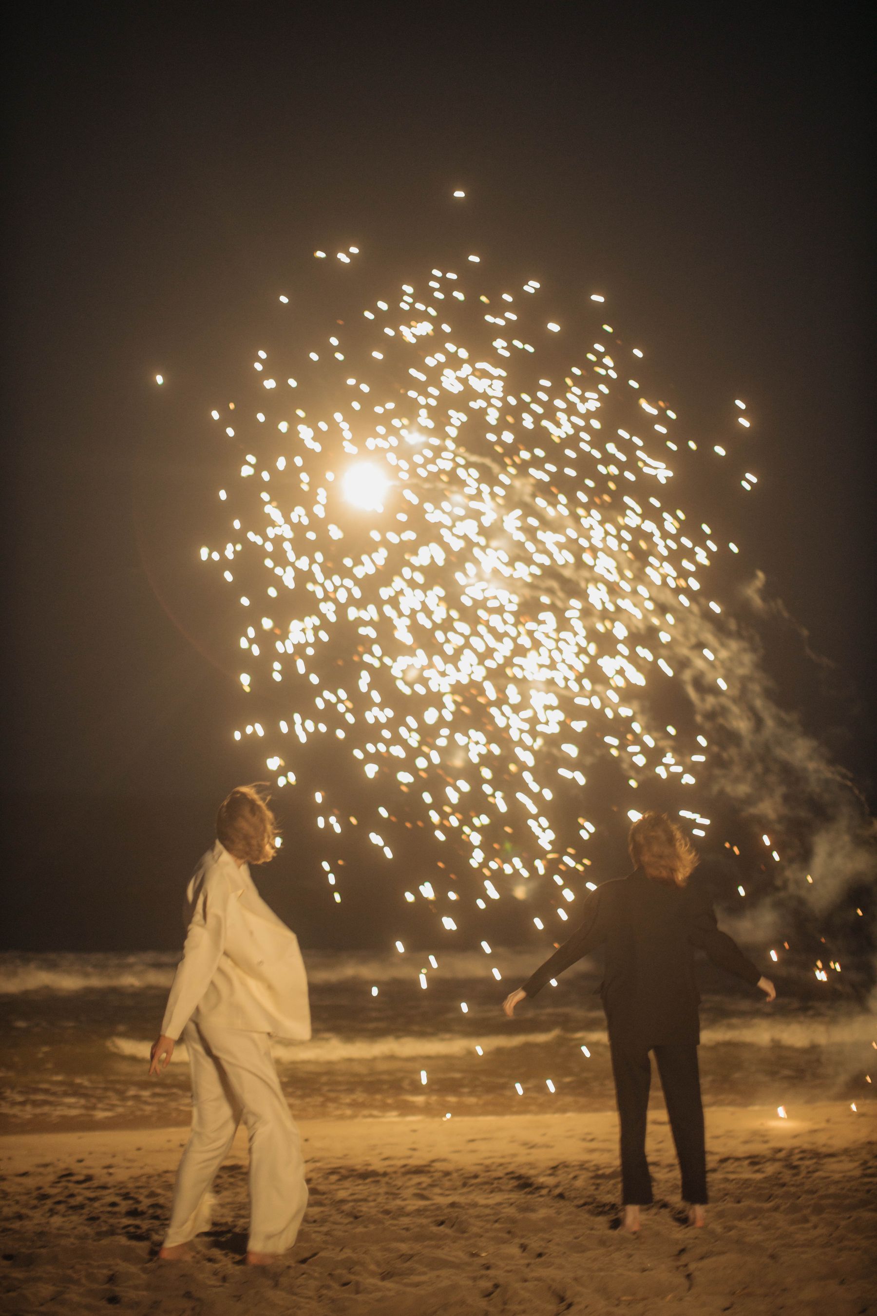 People watching fireworks from a beach at night