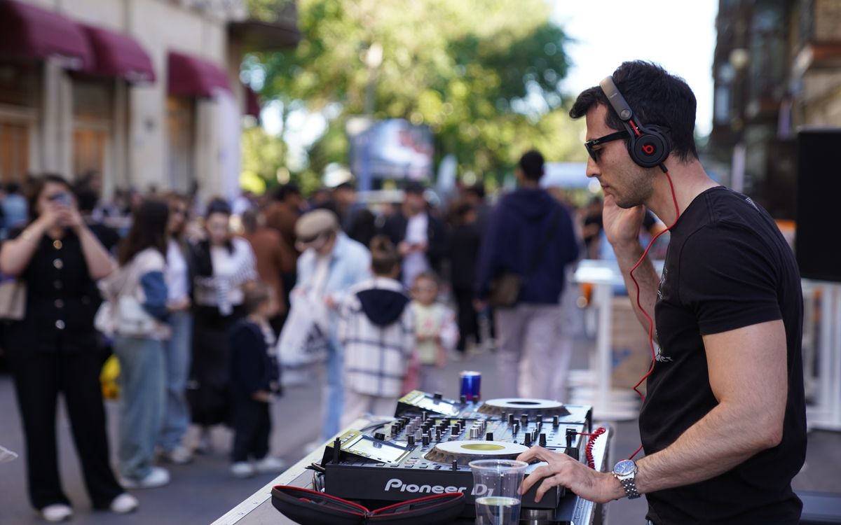 DJ performing at an outdoor event surrounded by a crowd
