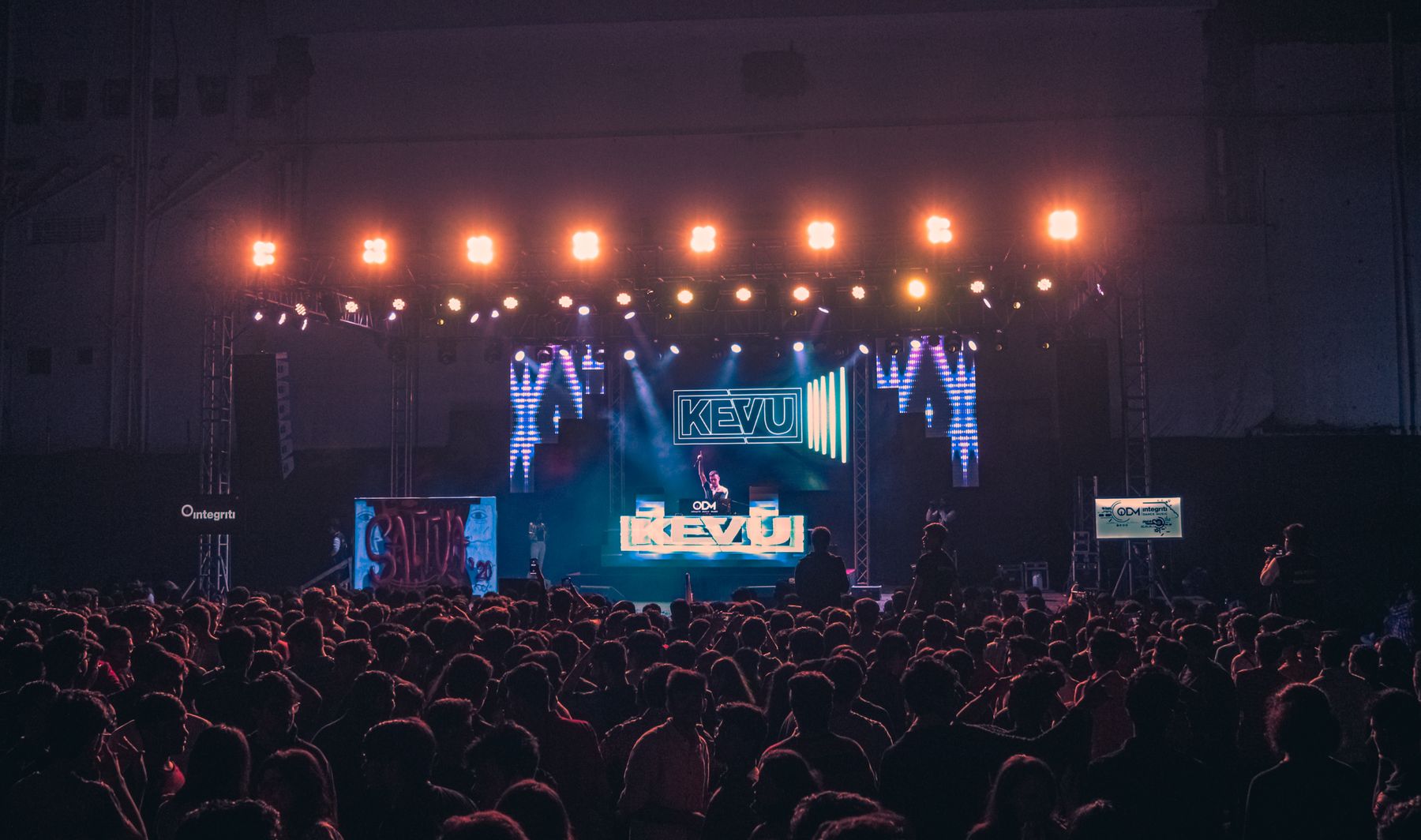 DJ performing beneath dramatic concert lighting