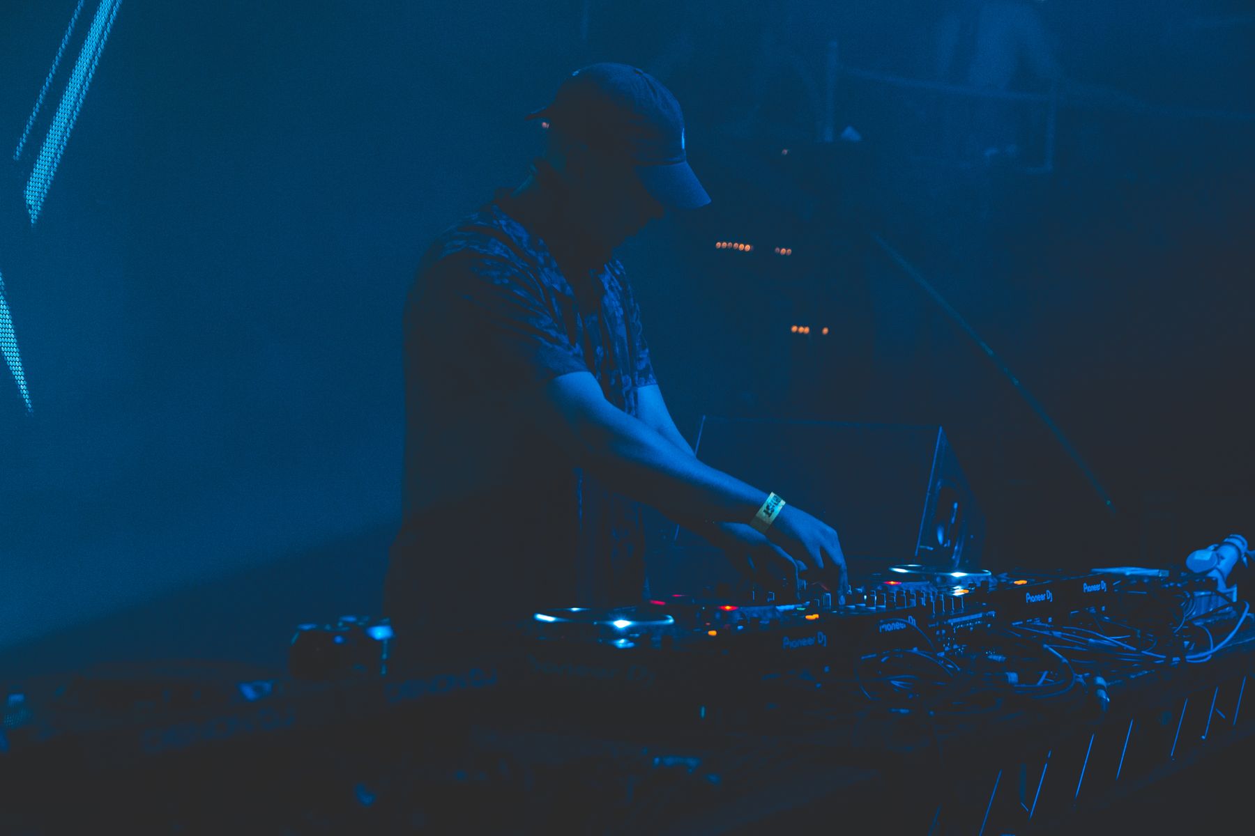 DJ performing to a nightclub crowd under coloured lights