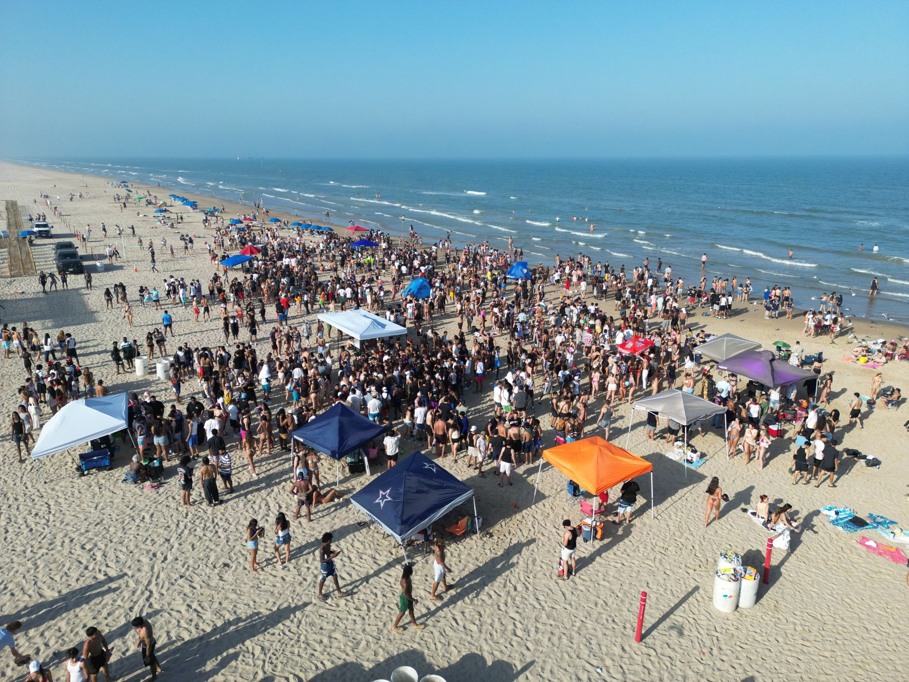 Large crowd gathering at a beach party beside the sea