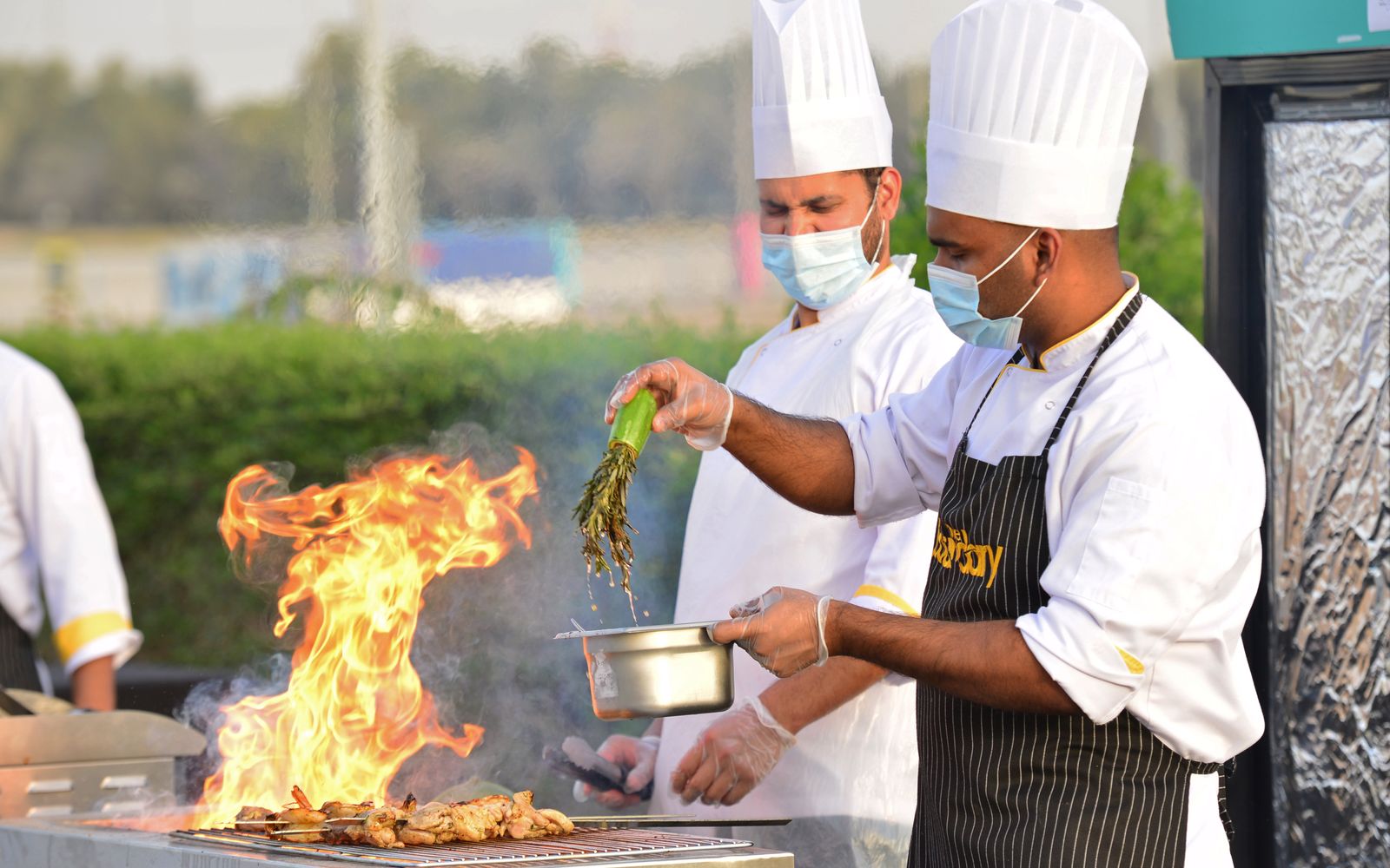 Chefs cooking together over an outdoor grill