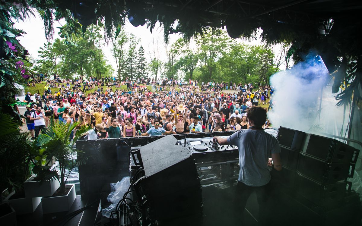 DJ playing to a crowd at an outdoor daytime festival