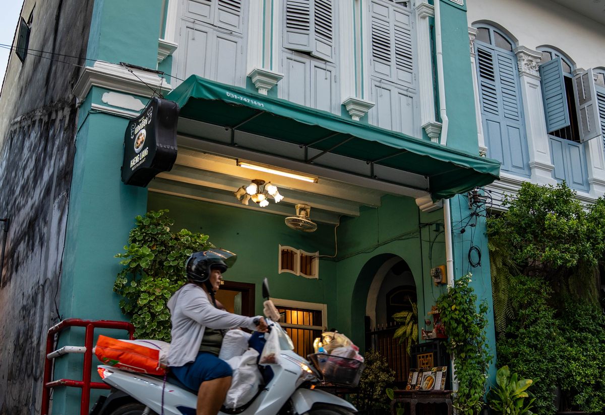 Motorcyclist passing colourful heritage architecture in Phuket Old Town