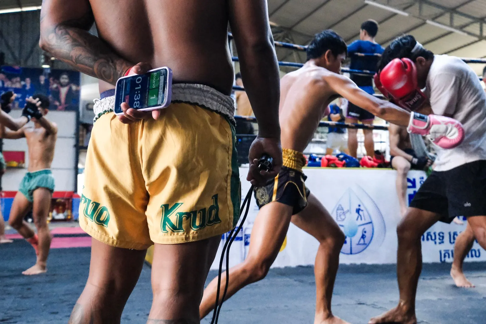Muay Thai fighters training together in a busy Thai gym