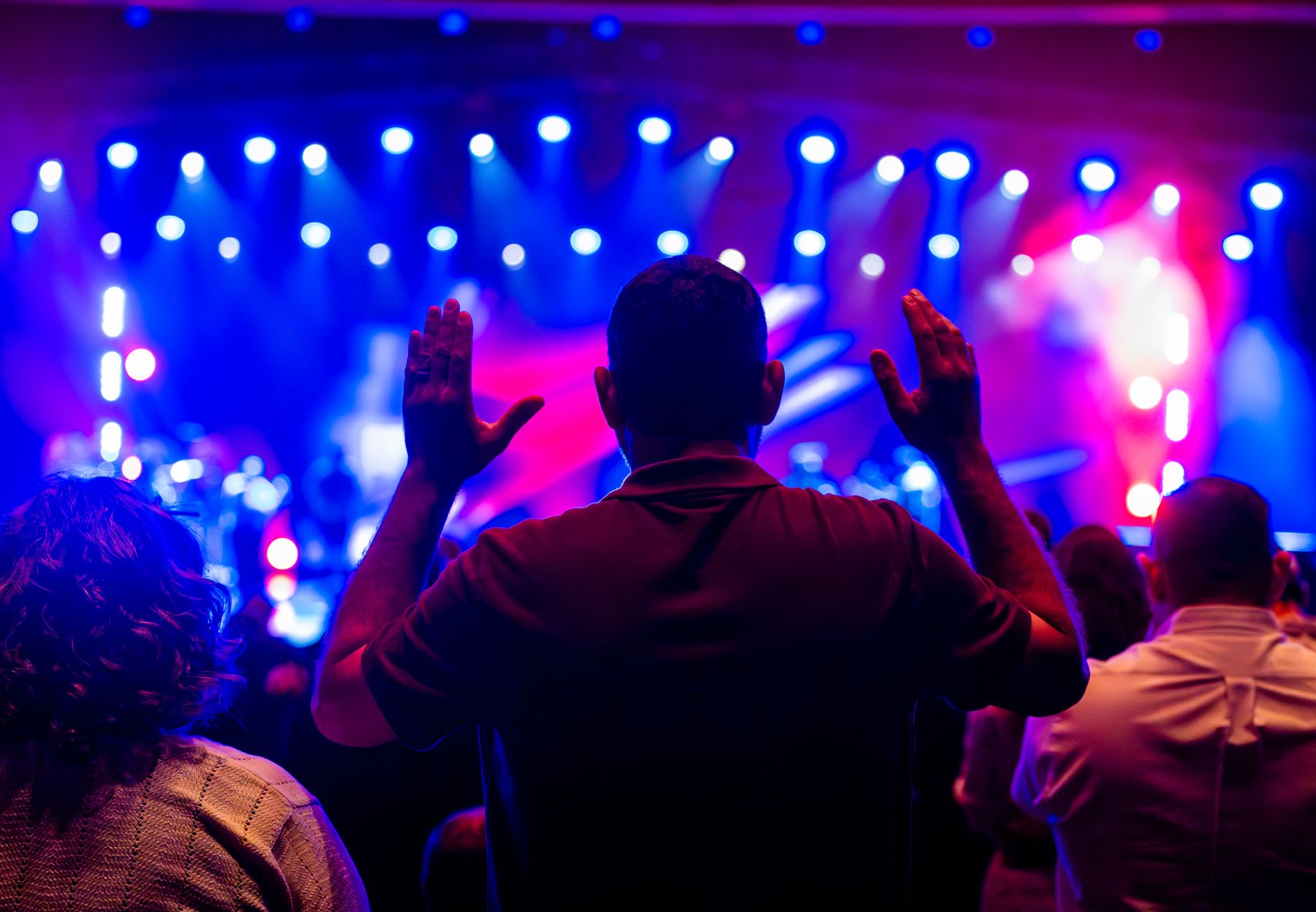 Audience watching a live performance beneath vivid stage lights