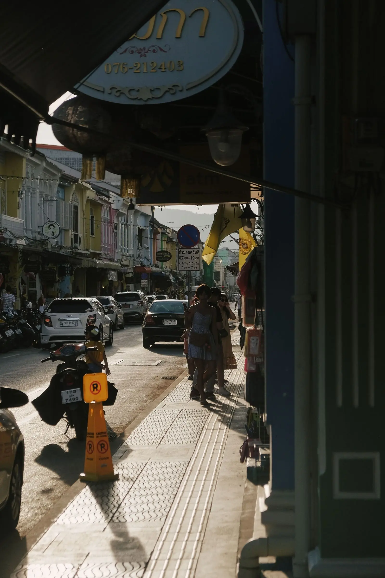 People sharing a busy late afternoon street in historic Phuket Town