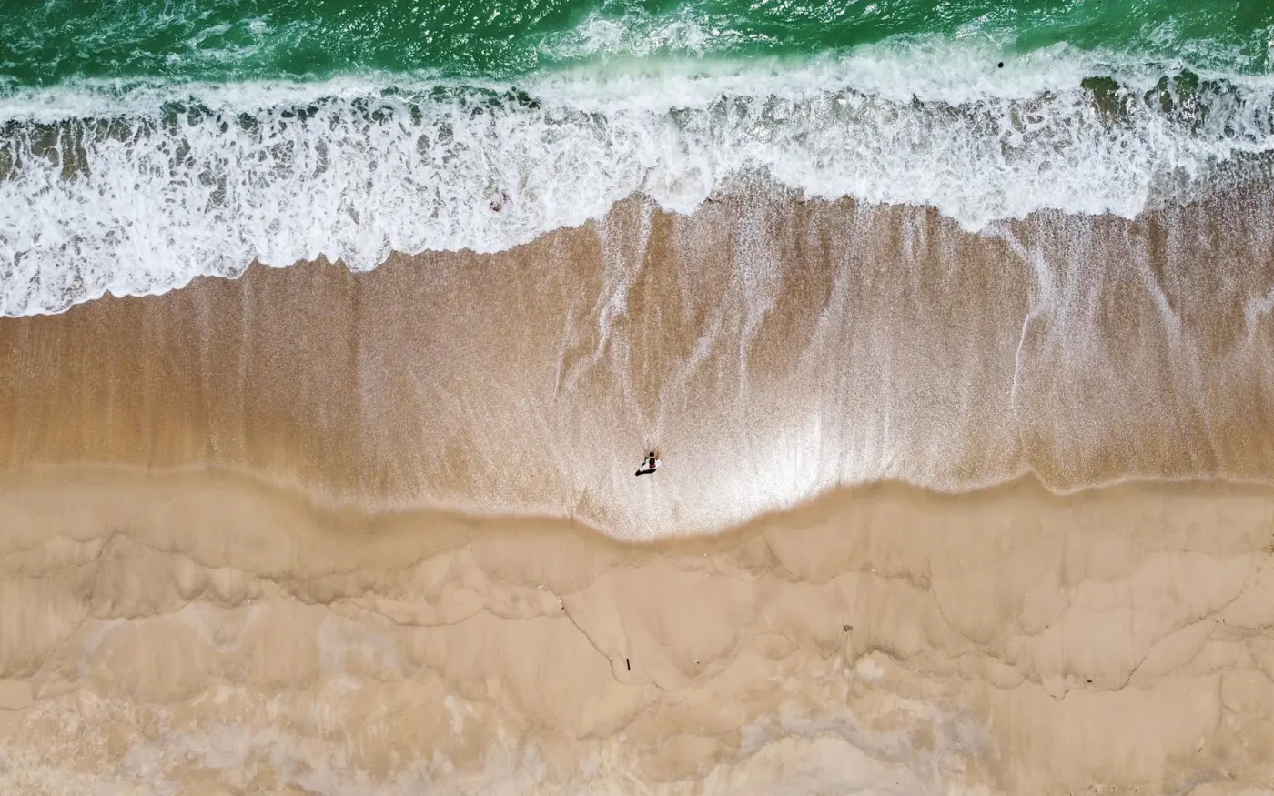 A lone surfer approaching the waves on a Phuket beach